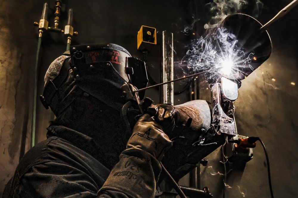 Welder at work with sparks in a dark booth